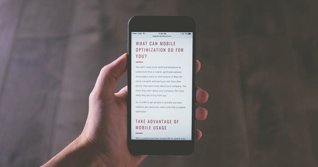 A hand holding a mobile phone with text on screen describing advantages of mobile-friendly design.