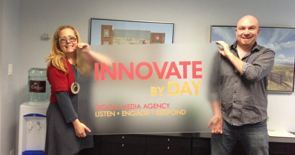 Deb Day and James Woods holding the signage for Innovate By Day, Digital Media Agency, marking the beginning of the business.